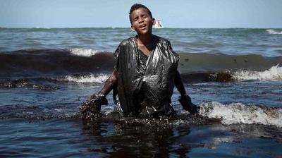La historia detrás de la foto del niño cubierto de petróleo en playas de Brasil